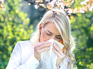 Kvinna med allergisk rinit. Nyser och snyter sig utomhus.