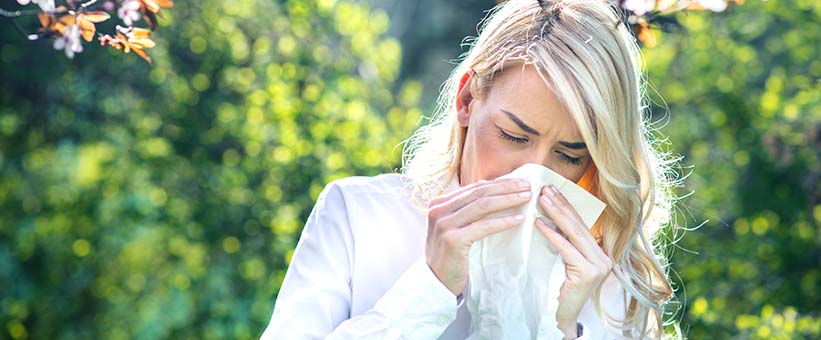 Kvinna med allergisk rinit. Nyser och snyter sig utomhus